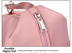 Macro shot of pink travel bag detail showing the sturdy metal zipper and nylon webbing handle