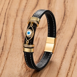 Dettaglio del bracciale punk in pelle nera con ciondolo occhio dorato e chiusura magnetica