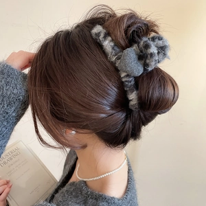 Détail d'une grande pince à cheveux en motif léopard portée sur un chignon bas