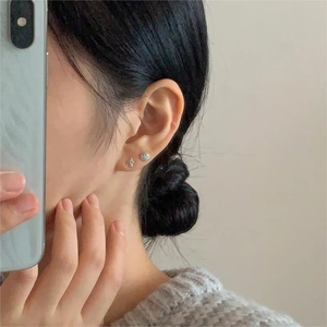 Close-up of a model wearing 925 silver star and round stud earrings in a minimalist style
