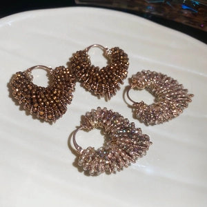 Detail of handcrafted heart-shaped beaded earrings with crystals in vintage bronze and purple