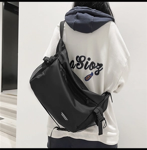 Detailed back view of a black nylon crossbody bag on a model wearing a white hoodie