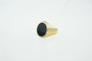 Macro shot of a high-polish gold signet ring featuring a centered oval black onyx stone