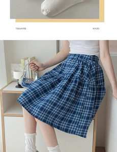 Detail of blue plaid skirt and white calf socks with Treasure Socks text in soft lighting
