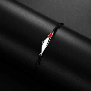 Detail of Palestine map charm on black woven cord bracelet with enamel flag colors
