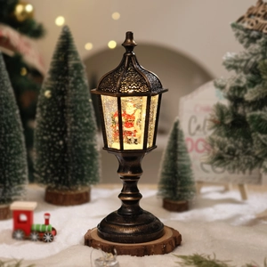 Close-up of lighted Santa Claus snow globe lantern on wood base with festive background
