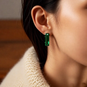Close-up of emerald-cut rectangular earrings with zircon stones on a model's ear