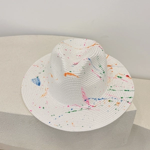 Detailed texture of white woven straw hat with vibrant colorful ink splatter design
