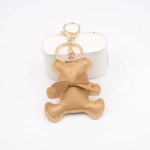 Detailed view of khaki PU leather bear keychain with golden metal ring and ribbon bow