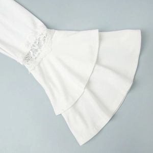 Détail de manche de robe blanche avec volants à plusieurs niveaux et broderie dentelle