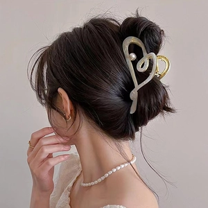 Elegant large acetate heart hair claw clip with pearl accents worn by a model