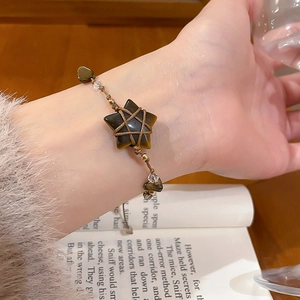 Macro detail of tiger eye star pendant and beaded boho bracelet on woman's wrist