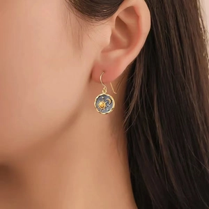 Detailed shot of celestial sun and moon charm earrings worn on a female model