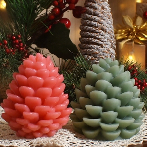 Pinecone shaped Christmas candles in pink and green with realistic scale textures
