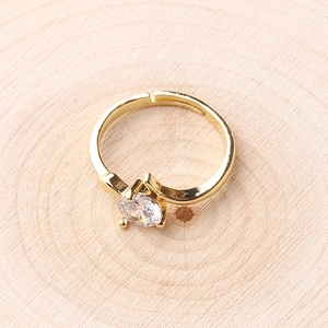 Close-up of a delicate gold ring featuring a four-prong set round cubic zirconia on a wooden base