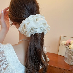 Close-up of a large white pleated chiffon scrunchie worn on a low ponytail hair style