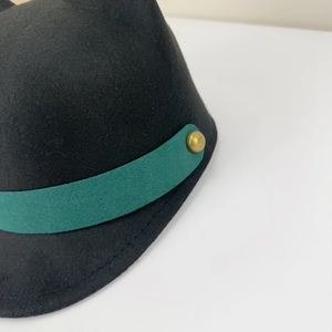 Detail of wool cap with dark green ribbon and golden metal rivet decoration