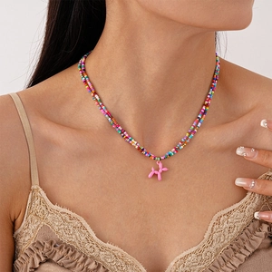 Collier en perles colorées avec pendentif chien ballon rose porté par un modèle