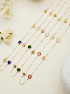 Vista de detalle de collares de corazón dorados con cristales y circonitas brillantes