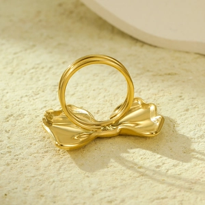 Elegant gold bow scarf ring and ring accessory on textured stone background