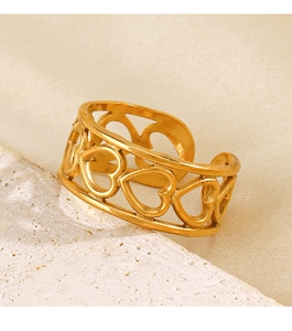 Detailed close-up of golden hollow heart ring on white marble and beige silk fabric