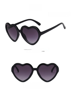 Detail view of heart-shaped kids sunglasses in glossy black frame with grey lenses