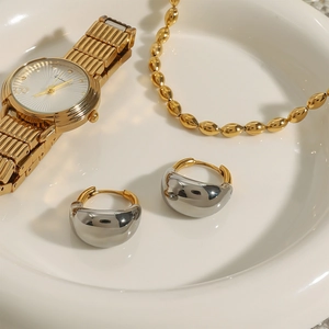 Two-tone 18K gold and silver chunky teardrop earrings on a white ceramic tray