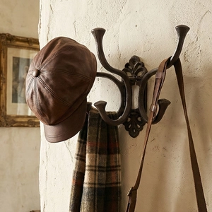 Vintage cast iron wall hook with European relief patterns on a rustic white wall