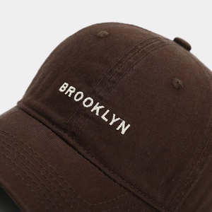 Close-up of white Brooklyn embroidery on a dark brown premium cotton baseball cap