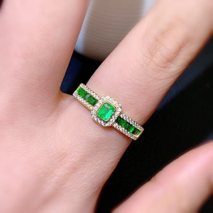 Macro shot of luxury gold emerald ring with side stones worn on a finger