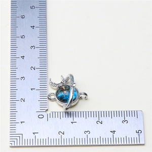 Detail view of blue star and moon pendant with dimensions on a measuring ruler