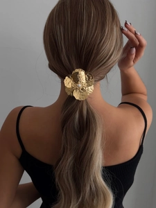 Detail of golden textured metal flower hair tie with pearl accent on a ponytail