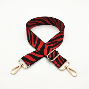 Close-up of zebra pattern woven bag strap with golden metal lobster clasps and buckle