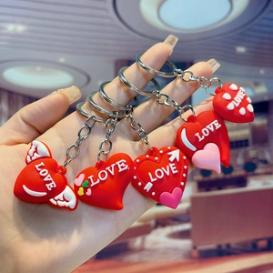 Set of four red PVC heart keychains with LOVE relief text and decorative wings