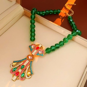 Detail of vintage flower pendant necklace featuring colorful crystals and green faceted beads
