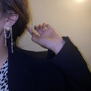 Detailed view of long tassel earrings with pearls and rhinestones on a female model
