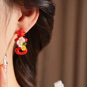 Traditional red Xi character earrings with small flowers shown on model's ear