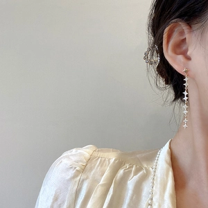Elegant long gold star drop earrings with micro-pave zircons worn by a model