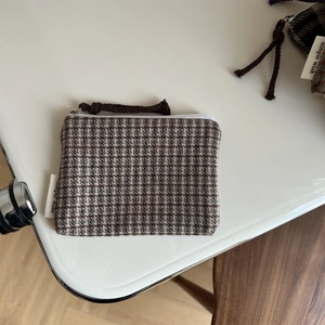 Macro shot of houndstooth wool coin purse with zipper closure and brown rope puller