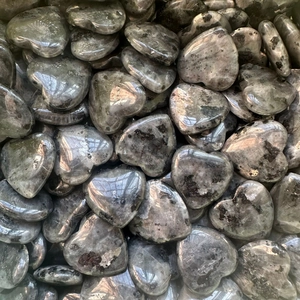 Close-up of numerous heart-shaped labradorite stones with natural grey luster and texture