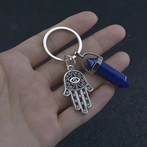 Detailed view of Hamsa Hand and blue crystal hexagonal pillar keychain on hand