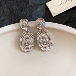 Macro detail of silver swirl textured earrings with elegant double oval shell design