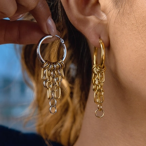 Close-up of gold and silver tassel chain earrings worn on ear for stylish look