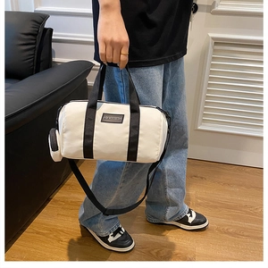 Detail of white nylon Boston bag featuring black straps and a mini charm pouch