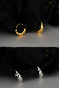 Close-up of chunky teardrop hoop earrings in polished gold and silver finishes