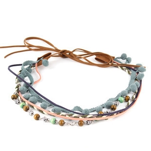 Detail of bohemian braided accessory with colorful tassels, wooden beads and pom-poms