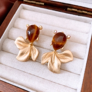 Detailed shot of vintage goldfish earrings with brown gemstones in a wooden jewelry box