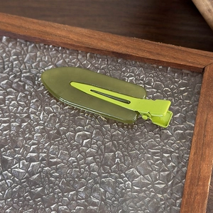 Primo piano di un fermaglio per capelli in resina verde oliva con base in metallo lime
