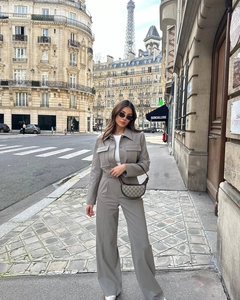 Dettaglio dei pantaloni a gamba larga a vita alta e giacca cropped in set grigio