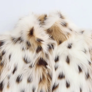 Detailed close-up of fluffy faux fur jacket texture in creamy white with brown spots